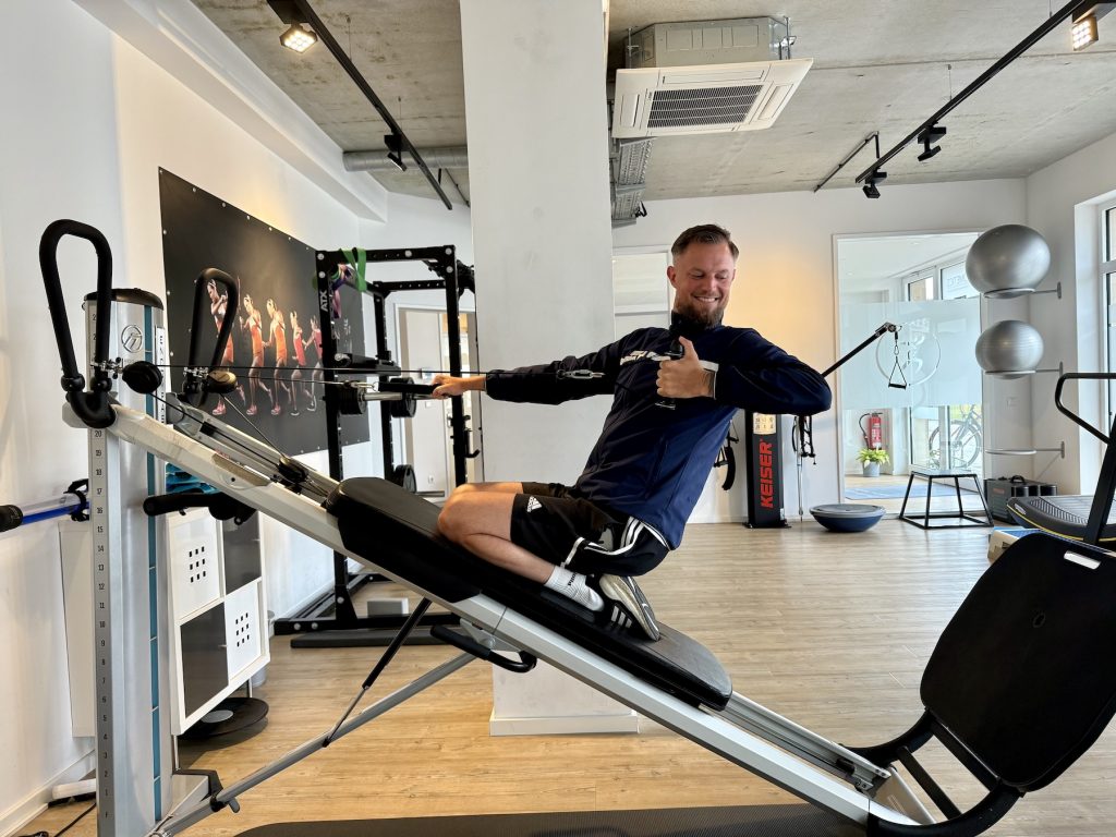 Ein junger Mann zeigt eine Übung an einem Fitness-Gerät